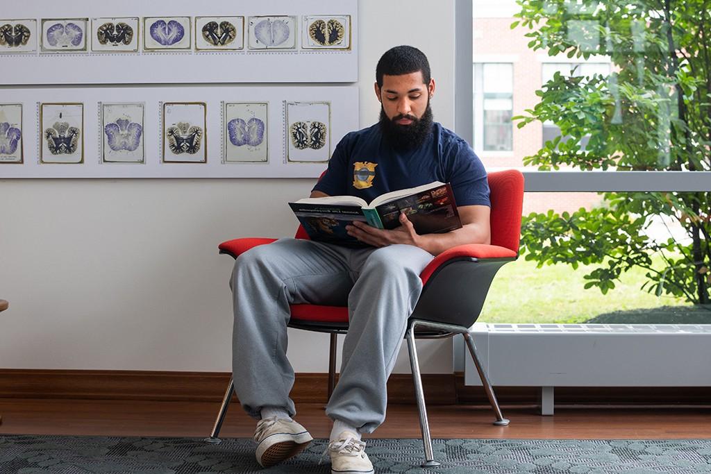 一名英国学生坐在艺术展览前的椅子上看书