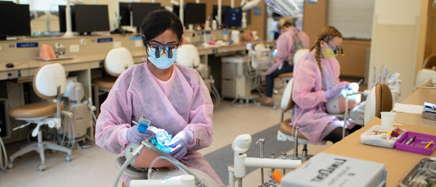 英国牙科学院的学生戴着磨砂膏在病人模拟器上进行口腔检查